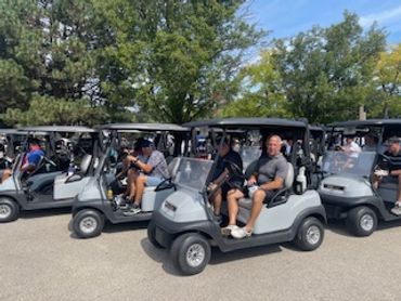 A group of people sitting in golf carts outdoors.
