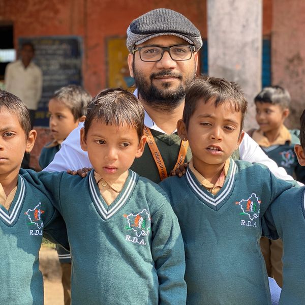 Man with four boys in school uniforms posing for a photo.