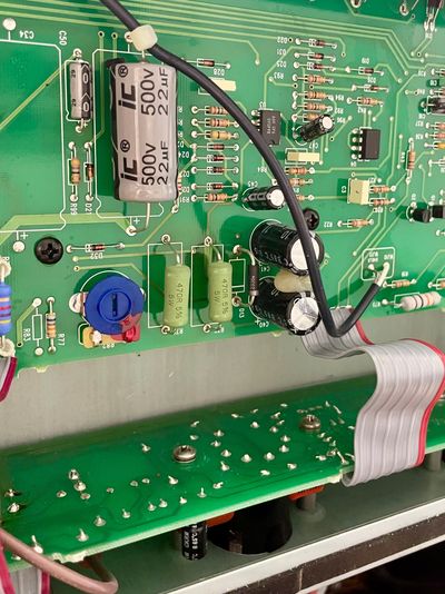 Close-up of an electronic circuit board with capacitors, resistors, and a ribbon cable.