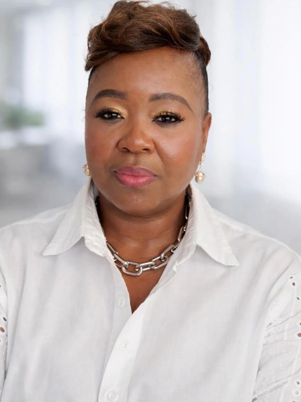 Confident woman with stylish short hair and white shirt in soft-light setting.