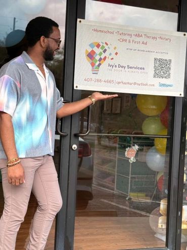 Man pointing to a sign for Ivy's Day Services on a glass door.