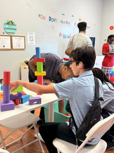 Boy building a colorful tower with blocks in a classroom.