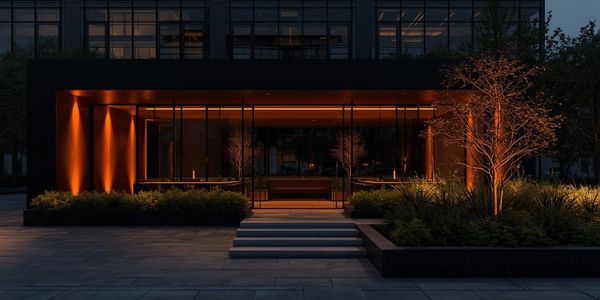Modern building entrance illuminated with warm orange lighting at night.