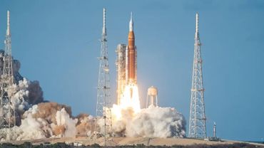 A rocket launches into the sky with smoke billowing at the base.
