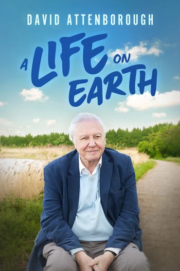 David Attenborough sits outdoors in a natural setting for 'A Life on Earth' documentary.
