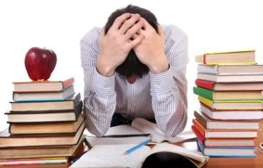 Frustrated man overwhelmed with studying, surrounded by stacks of books.