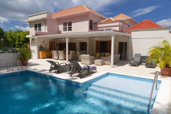 Luxurious house with a swimming pool and outdoor seating area under a covered patio.