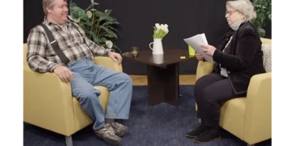 Chief Don Stevens sitting in a yellow chair talking to Juliana Anderson  of Vermont Byways.