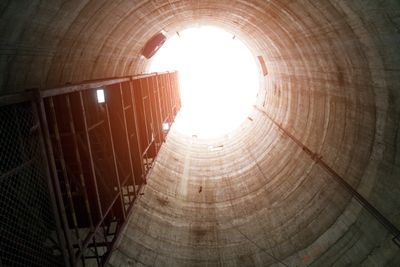 View looking up from inside a tall, cylindrical concrete structure toward a bright opening.