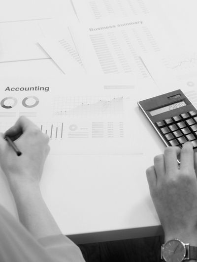Person working on accounting with calculator and charts on desk.