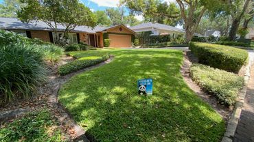 Well-maintained suburban lawn with a small advertisement sign in the center.