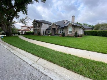 Modern suburban house with a well-maintained lawn and sidewalk under a cloudy sky.