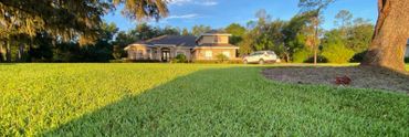 A large house with a neatly mowed lawn and a white car parked outside.