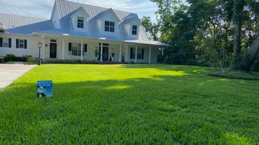 A white house with a metal roof and a well-maintained green lawn.