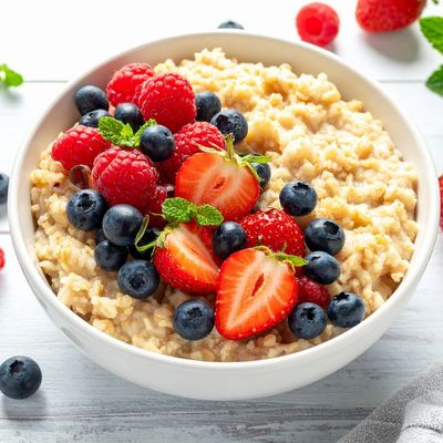 Bowl of oatmeal topped with fresh berries and mint.