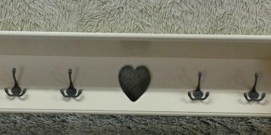 Wooden wall hook rack with heart design and five hooks.