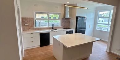 Bright modern kitchen with white cabinetry and wooden floors.