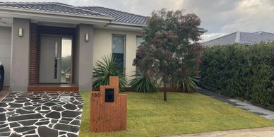Modern house entrance with a patterned driveway and wooden mailbox.