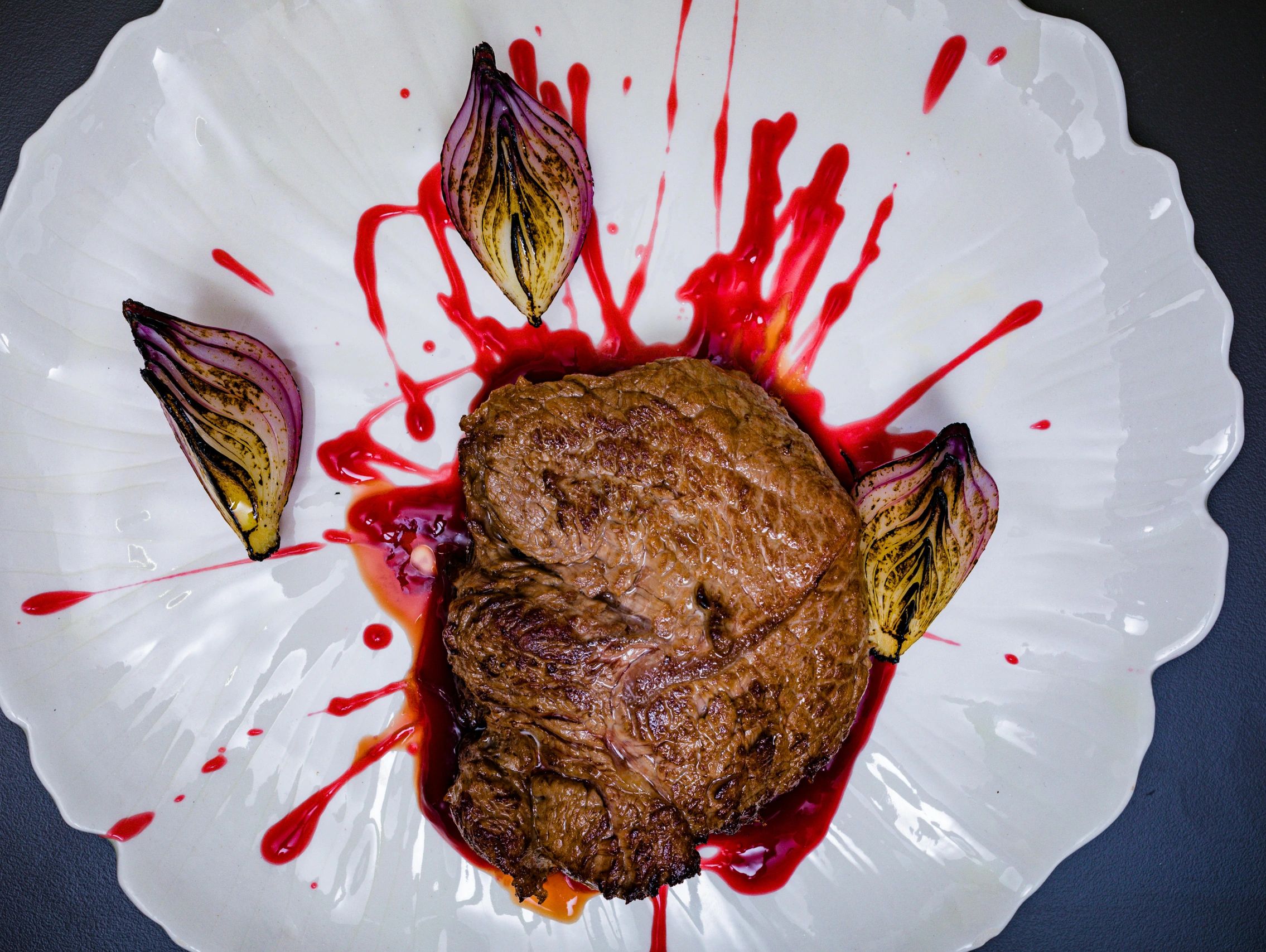 Ribeye with onions plated on pan sauce.