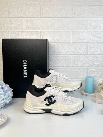 White Chanel sneakers with black accents and logo beside a Chanel box.