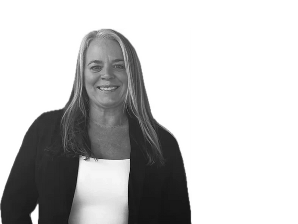 Smiling woman in casual attire with hands in pockets.