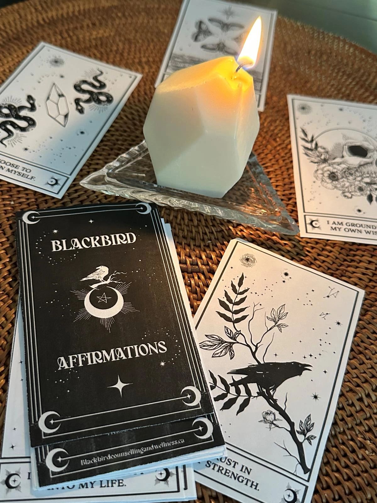 Blackbird positive affirmation cards on a table with a candle burning
