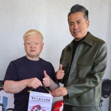 两名男子竖起大拇指合影。