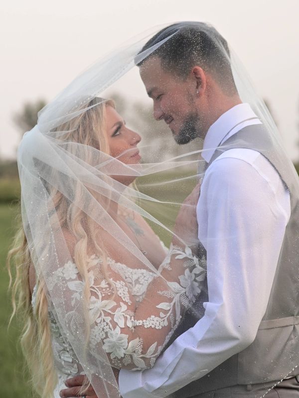 Bride and groom share a tender moment under the veil.