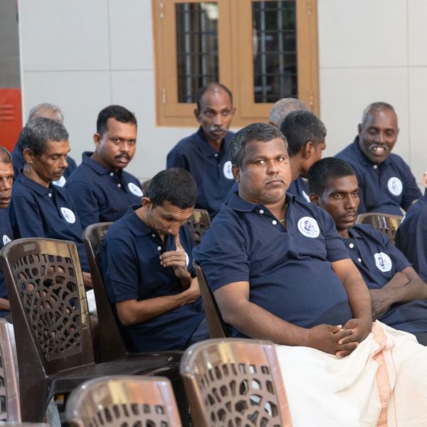 A group of men in matching navy blue shirts seated indoors.