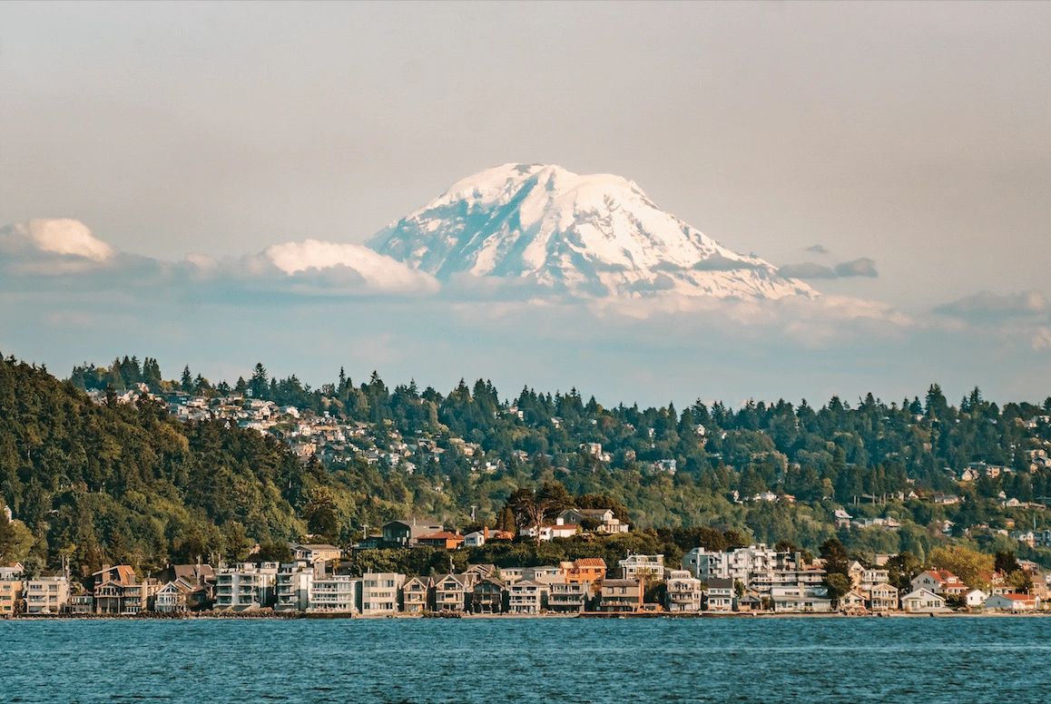 buildings next to a lake with a mountain in the background