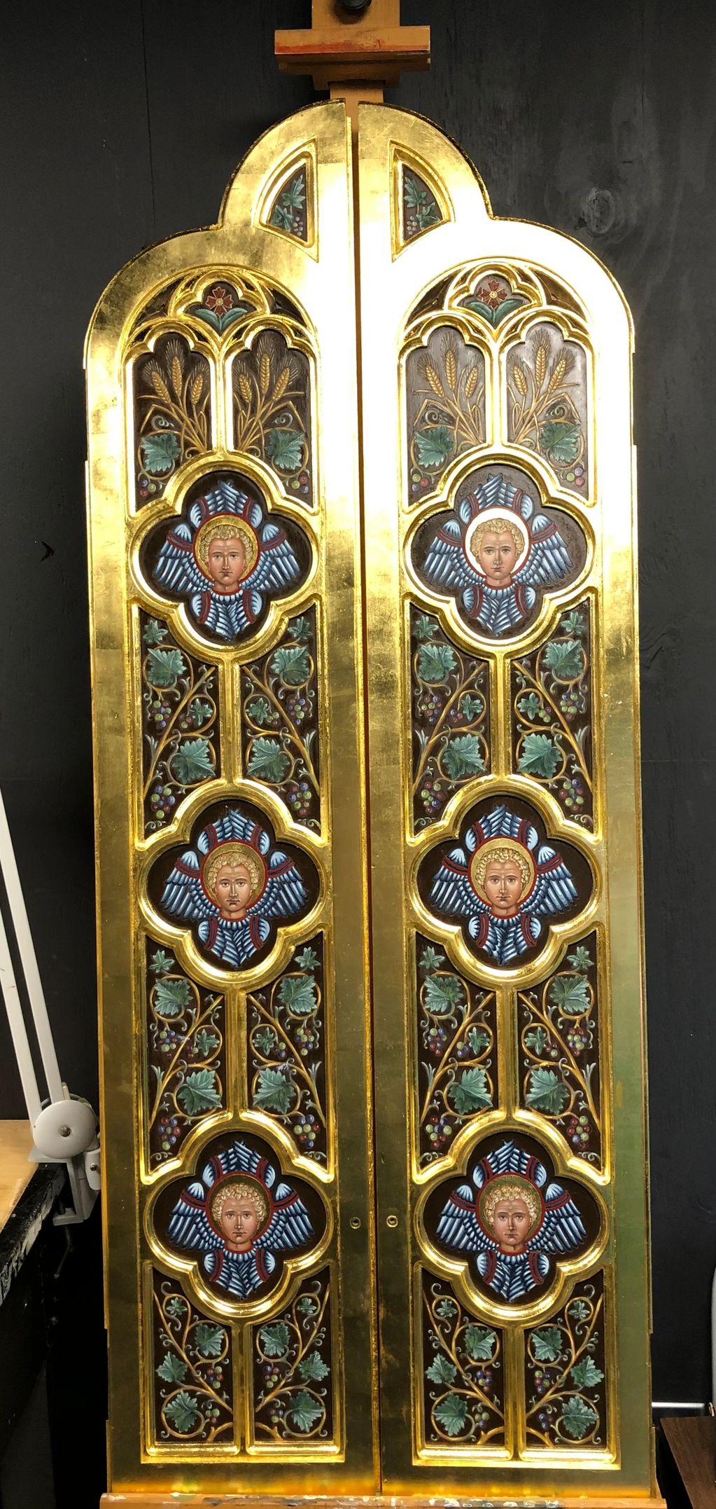 Gold and colorful religious panel with angelic faces and floral designs.