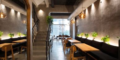 Modern cafe interior with wooden tables, black seating, and warm lighting.