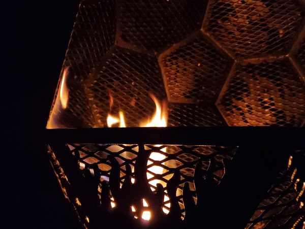 Wood burning in a geodesic fire pit by the metal fabricators at the Koi Lagoon.