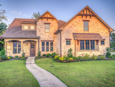Beautiful two-story brick house with a manicured lawn and curved walkway.