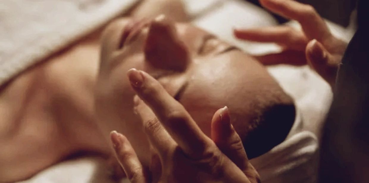 Person receiving a relaxing facial massage with gentle hand movements.