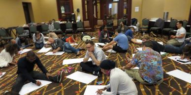 SJTI participants sitting on the floor doing an activity with newsprint paper. 