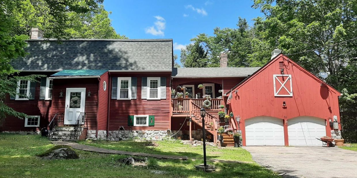 Red house with white accents and a double garage under a clear blue sky.