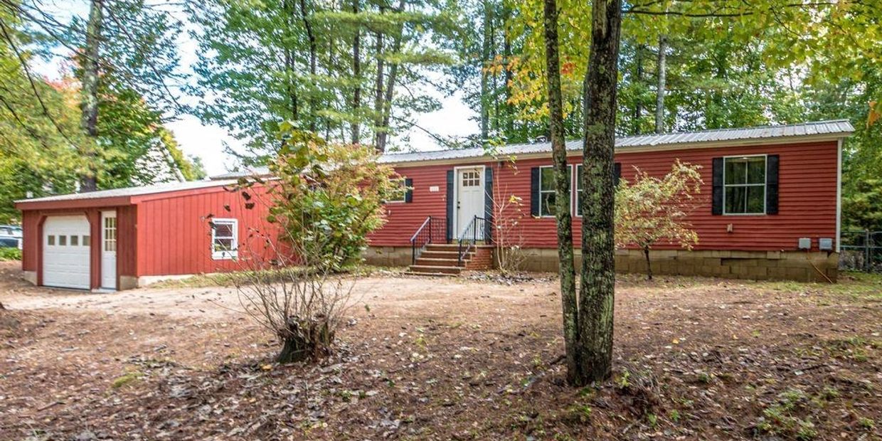 Red house with attached garage surrounded by trees.