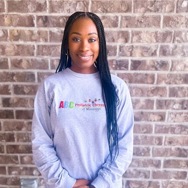 Woman standing in front of a brick wall wearing a gray sweatshirt.