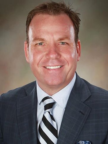 Smiling man in a suit and striped tie.