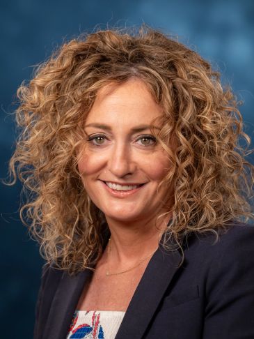 Smiling woman with curly hair in professional attire.