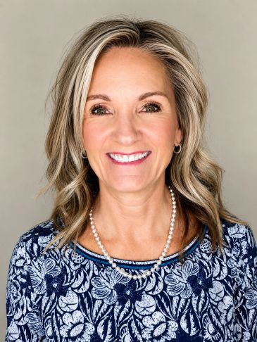 Smiling woman with blonde hair and a floral top.