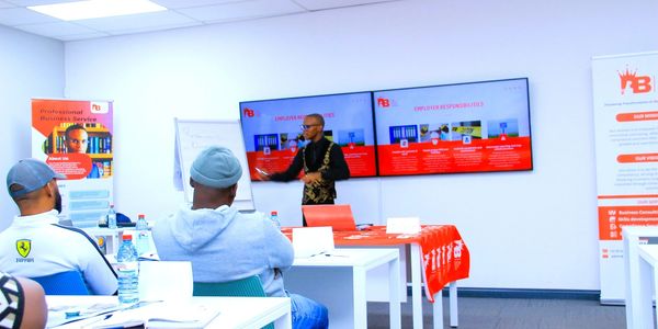 A presenter explains business services to an attentive audience in a modern conference room.