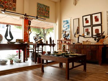Art gallery with sculptures and framed artwork in a cozy, sunlit room.