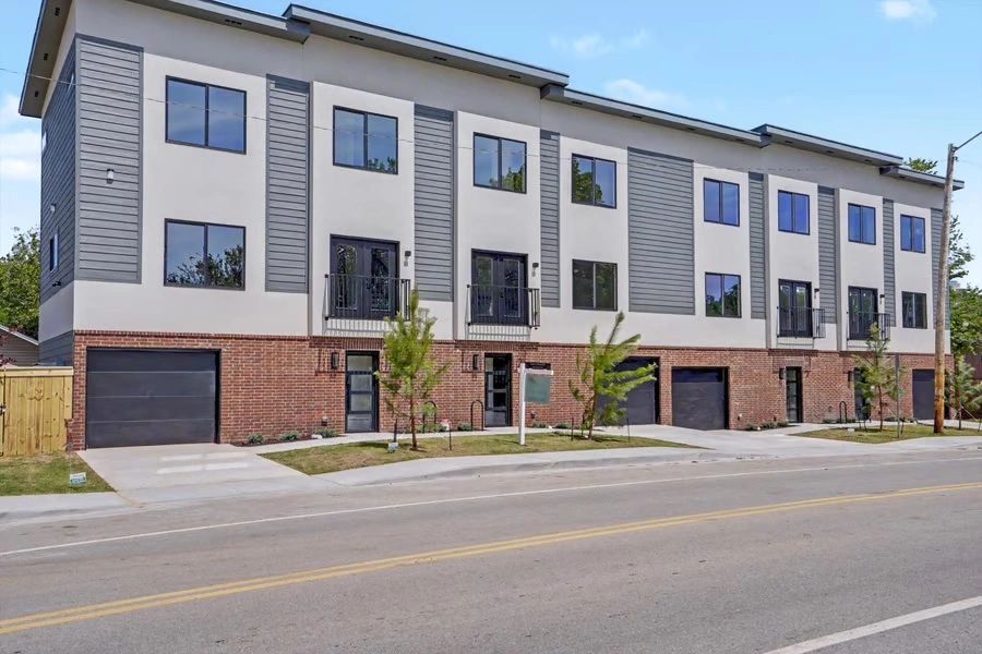 Modern three-story apartment building with garages and balconies.