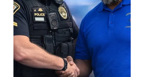 Police officer and community member shaking hands in solidarity.