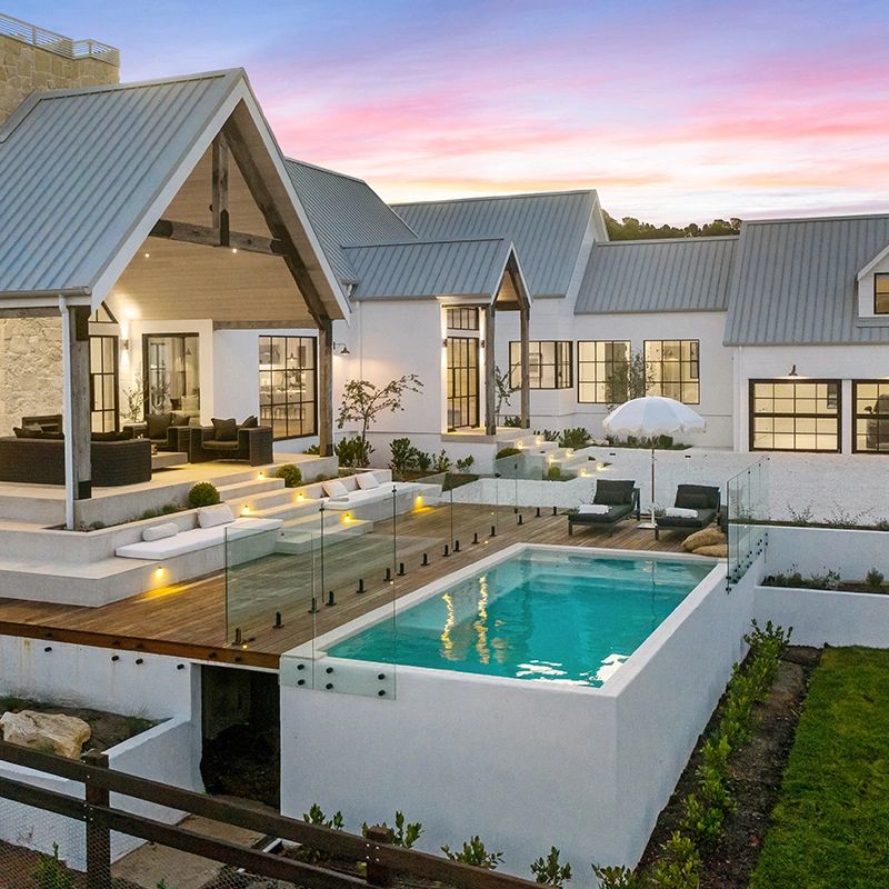 Modern white house with a glass-fenced pool at sunset.