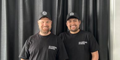 Two smiling men in black shirts and caps.