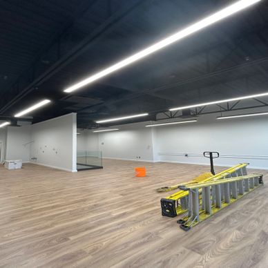 Empty commercial space with wooden flooring and lighting strips.