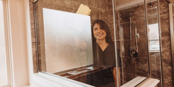 Aline of Grace Home Cleaning cleaning a glass shower in Rockwall, TX